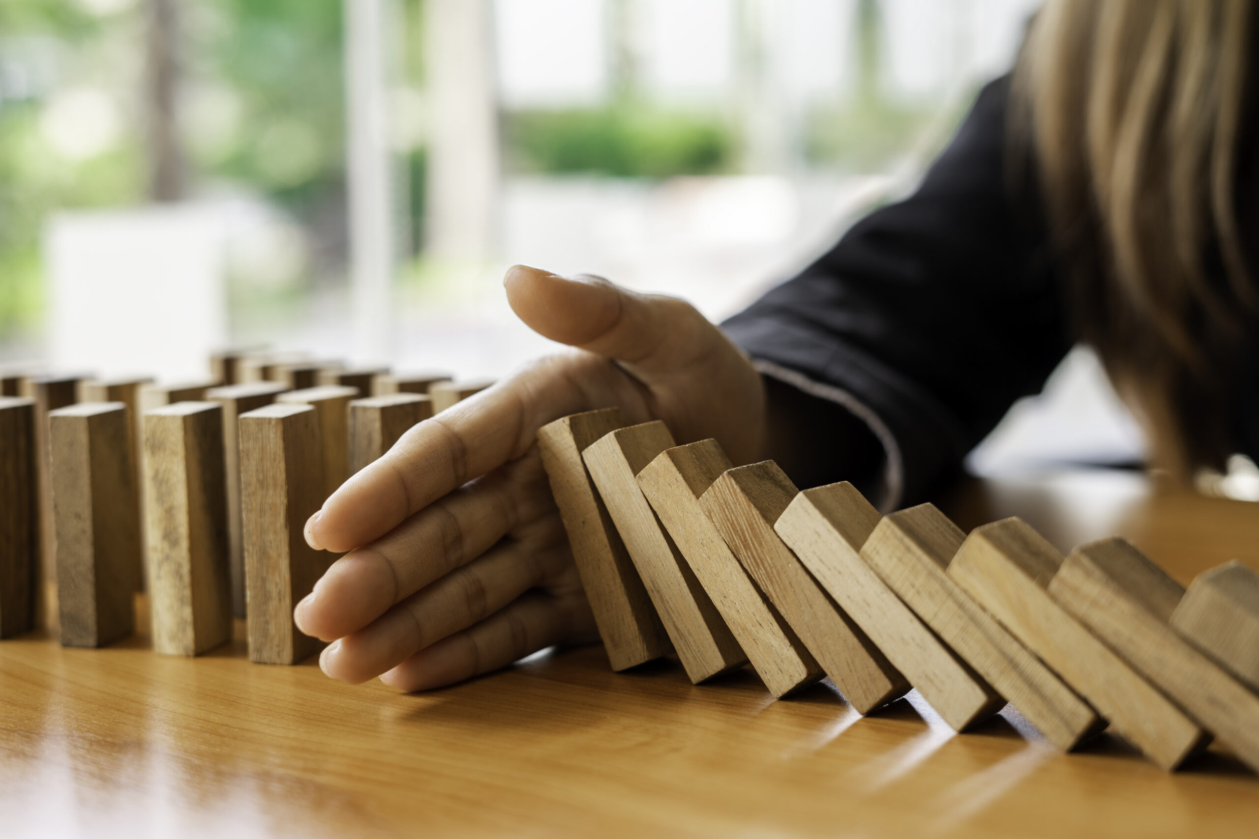 a-businesswoman-blocks-a-falling-wooden-block-like-2026-03-19-01-52-51-utc